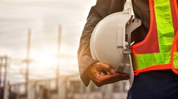 A construction worker stands holding a hard hat, ready for safety on the job site.