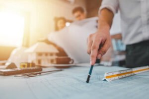 A man examines a blueprint while holding a ruler, focused on precise measurements and planning.