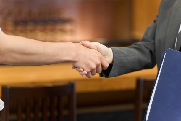 wo individuals shaking hands in a courtroom, representing a Franchise Construction agreement.